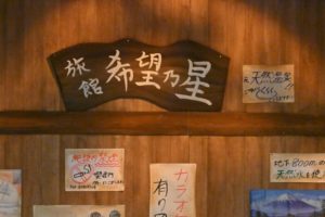 「旅館希望乃星」の看板。すぐ横に、「元天然温泉」の貼り紙。