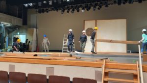 広い舞台に道具を置いて組み立てるスタッフさんとメンバーたち