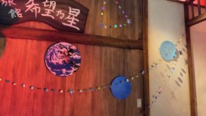 ２幕の旅館ロビー壁　惑星やキラキラした星のモールが飾られています。夏の大三角形も！